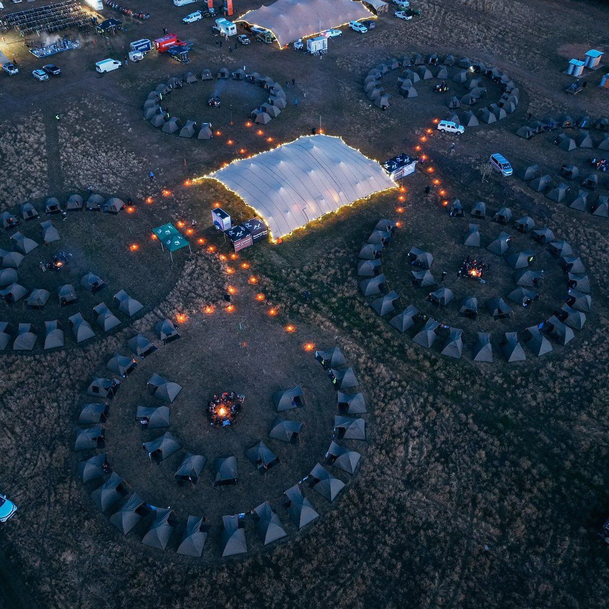 A Burn Camp from above at dusk: circles of tents around their fires